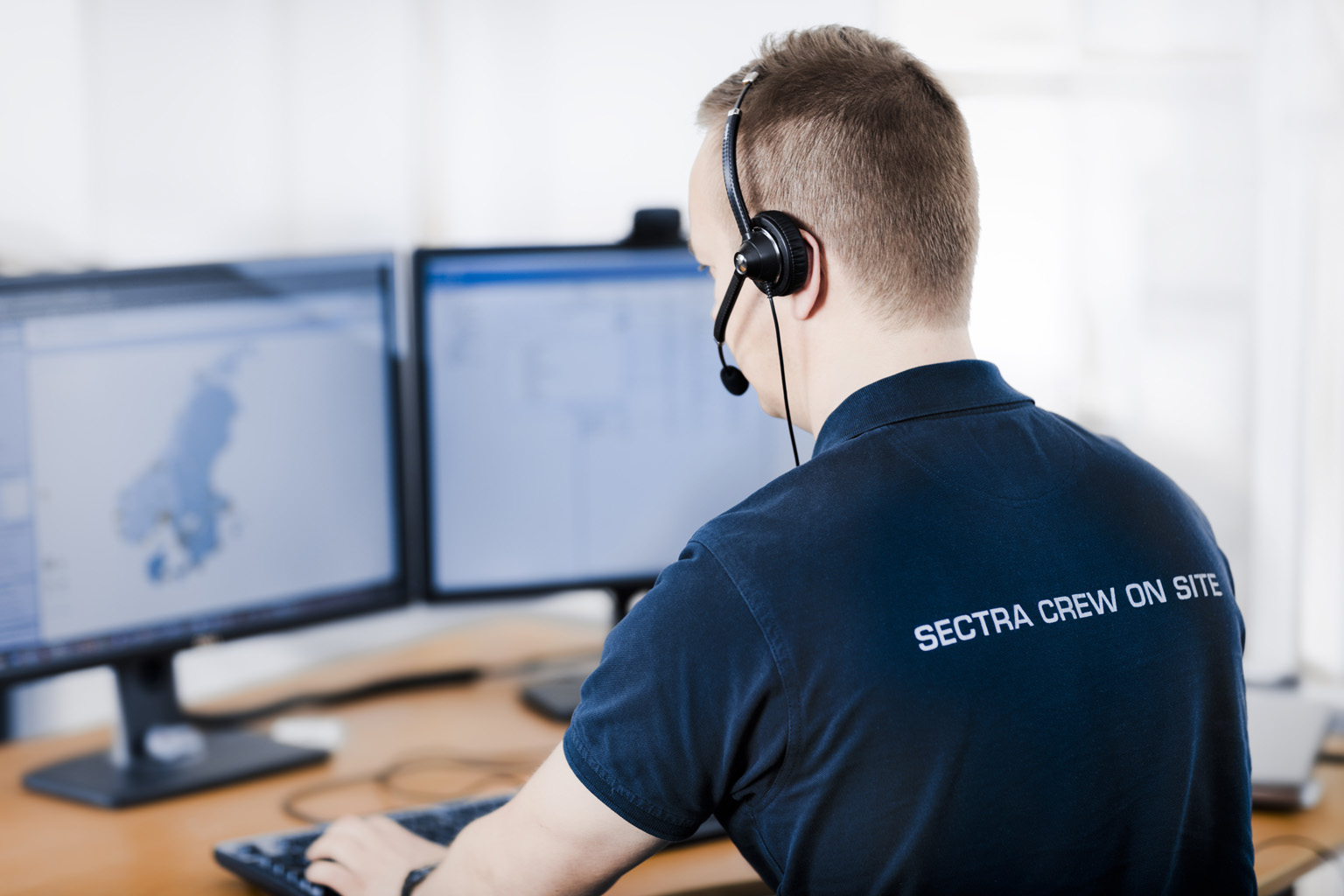 A male Sectra support representative working with headset by his computer