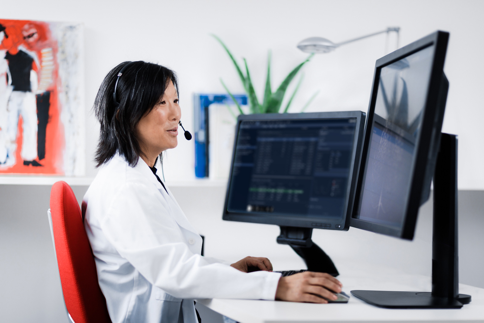 Female radiologist with headset, discussing a breast imaging case on tele-conference.