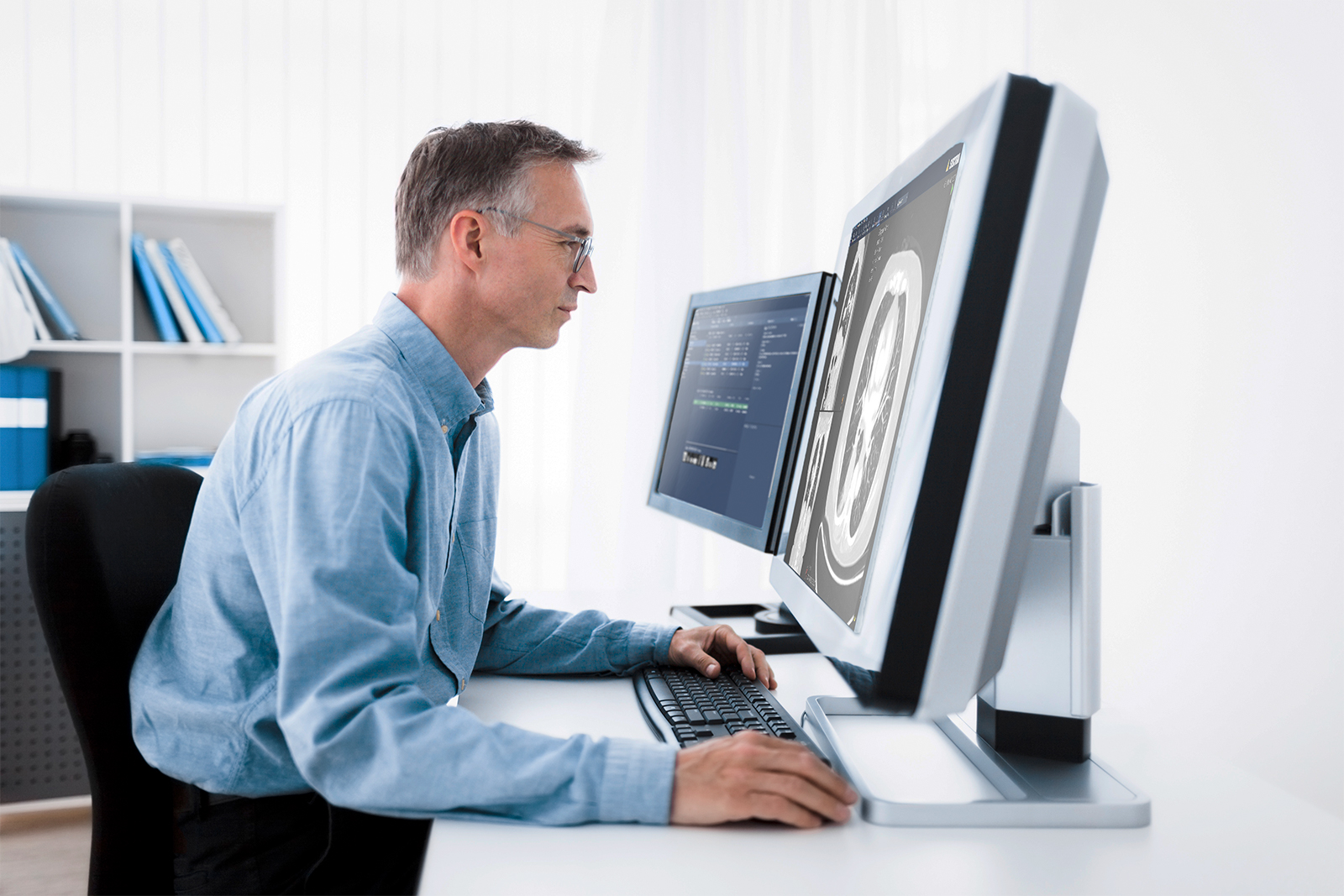 Male radiologist looking at CT scans on his monitor, using Sectra PACS.