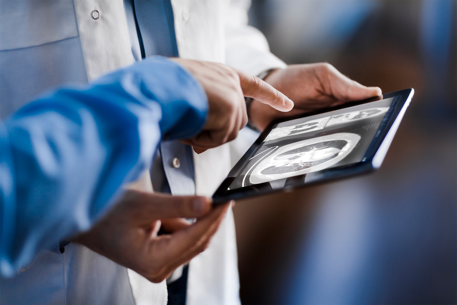 Close-up of a doctor showing a colleague or patient medical images on a tablet using Sectra UniView.