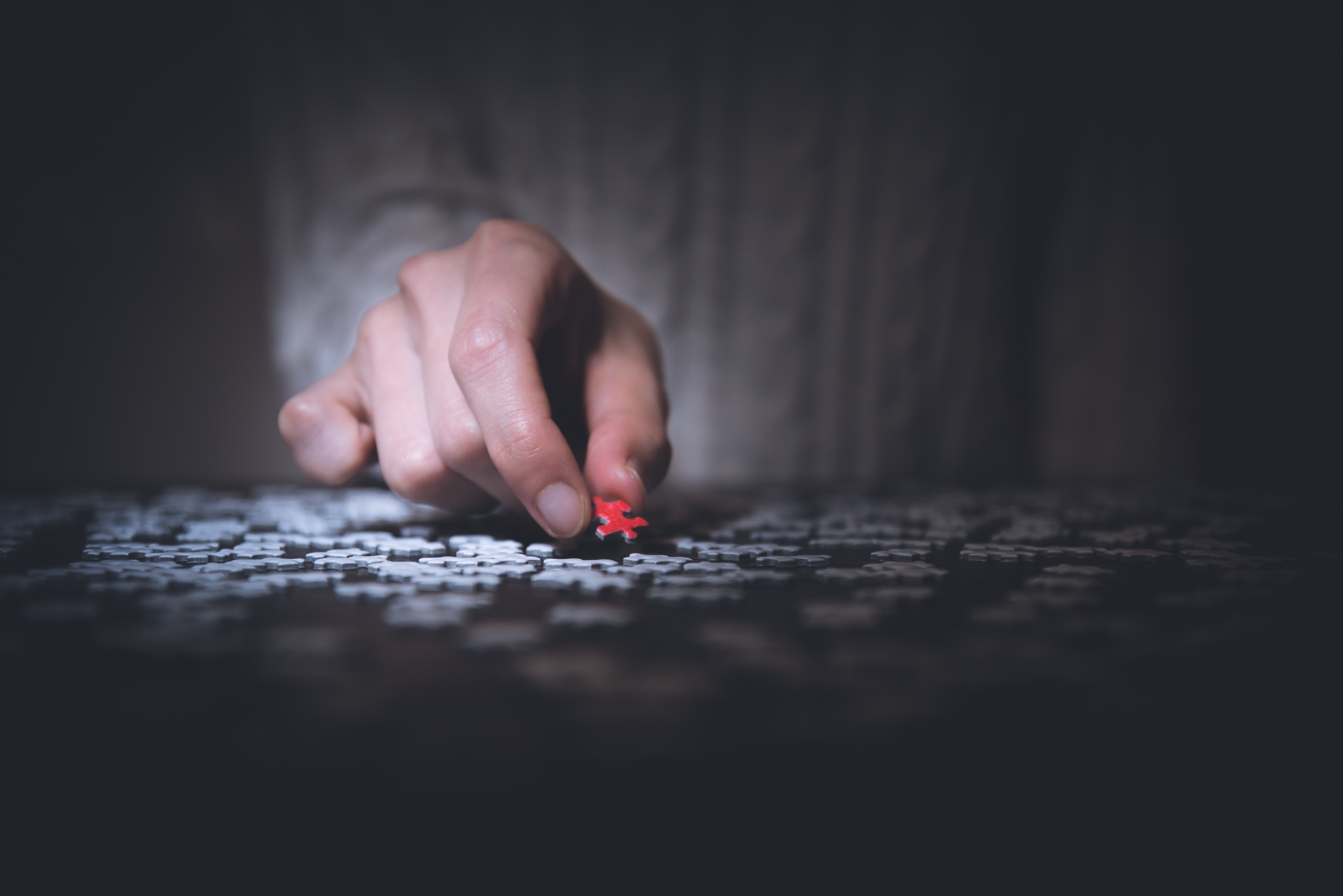 Close-up of a hand holding a red puzzle piece