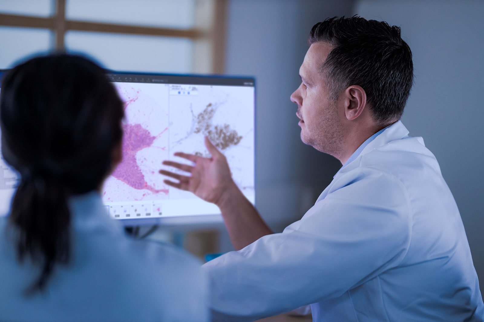 Two pathologists studying a digital pathology case on a monitor