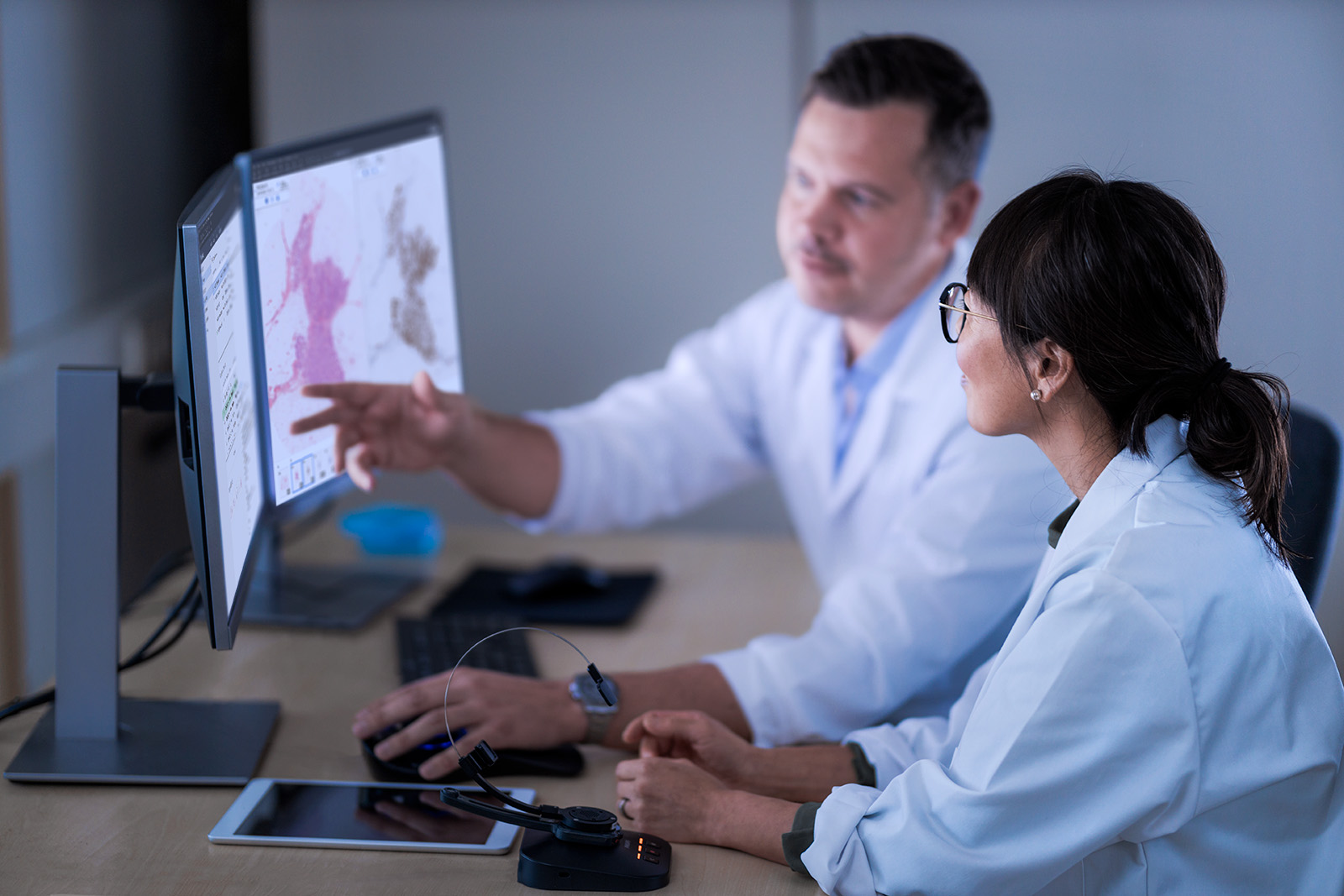 Two pathologist in front of a monitor discussing a case