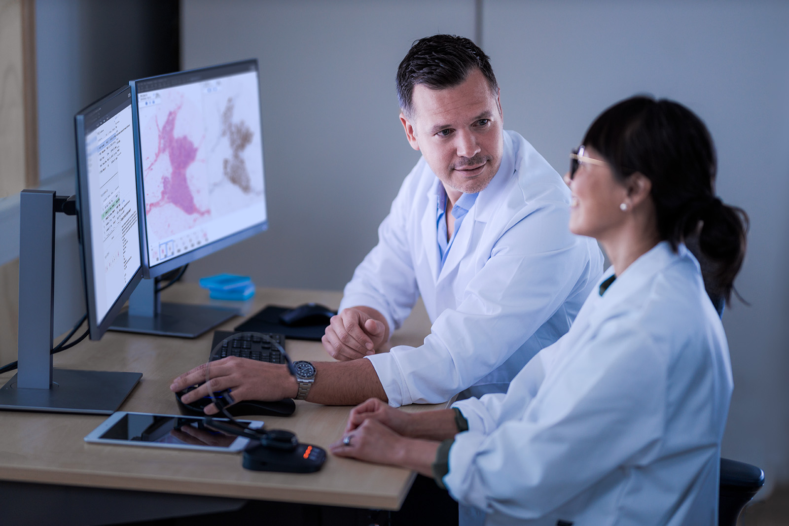 Two pathologist in front of a monitor discussing a case