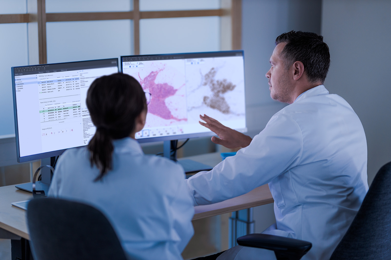 Two pathologists in front of a monitor discussing a case