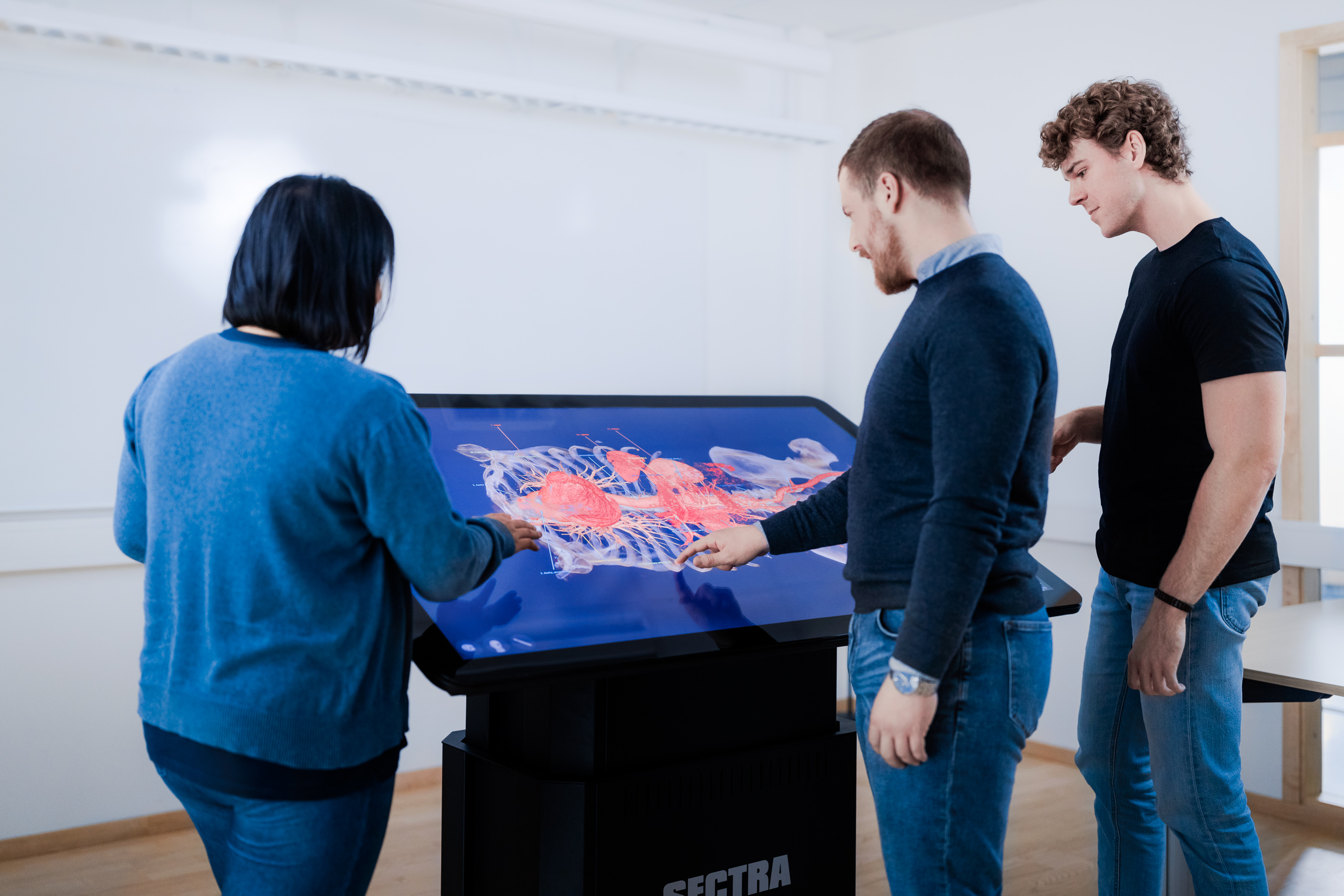 Three students interacting with medical image on the Sectra table